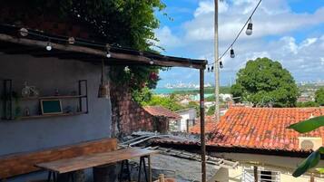 Uma área de estar ao ar livre com piscina, banquinhos de madeira e vista para a cidade.
