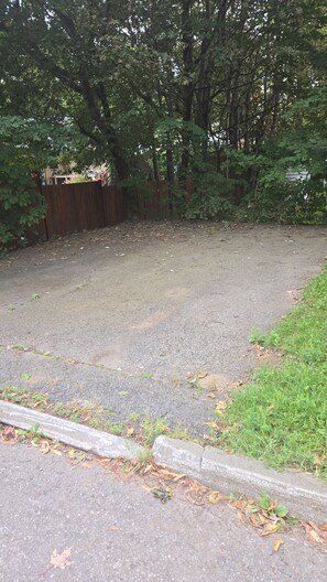 A paved area with a wooden fence, surrounded by trees and grass. - A cozy home just outside Quebec City. Pets are allowed. (Québec)