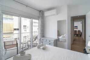 Ein Hotelzimmer mit einem Bett, einem Schreibtisch, einem Stuhl, einem großen Fenster und Blick ins Freie.