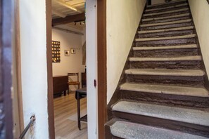 Eine Treppe mit Holzsitzen und Handlauf, die zu einem Zimmer mit einem Bett und einem Stuhl führt.