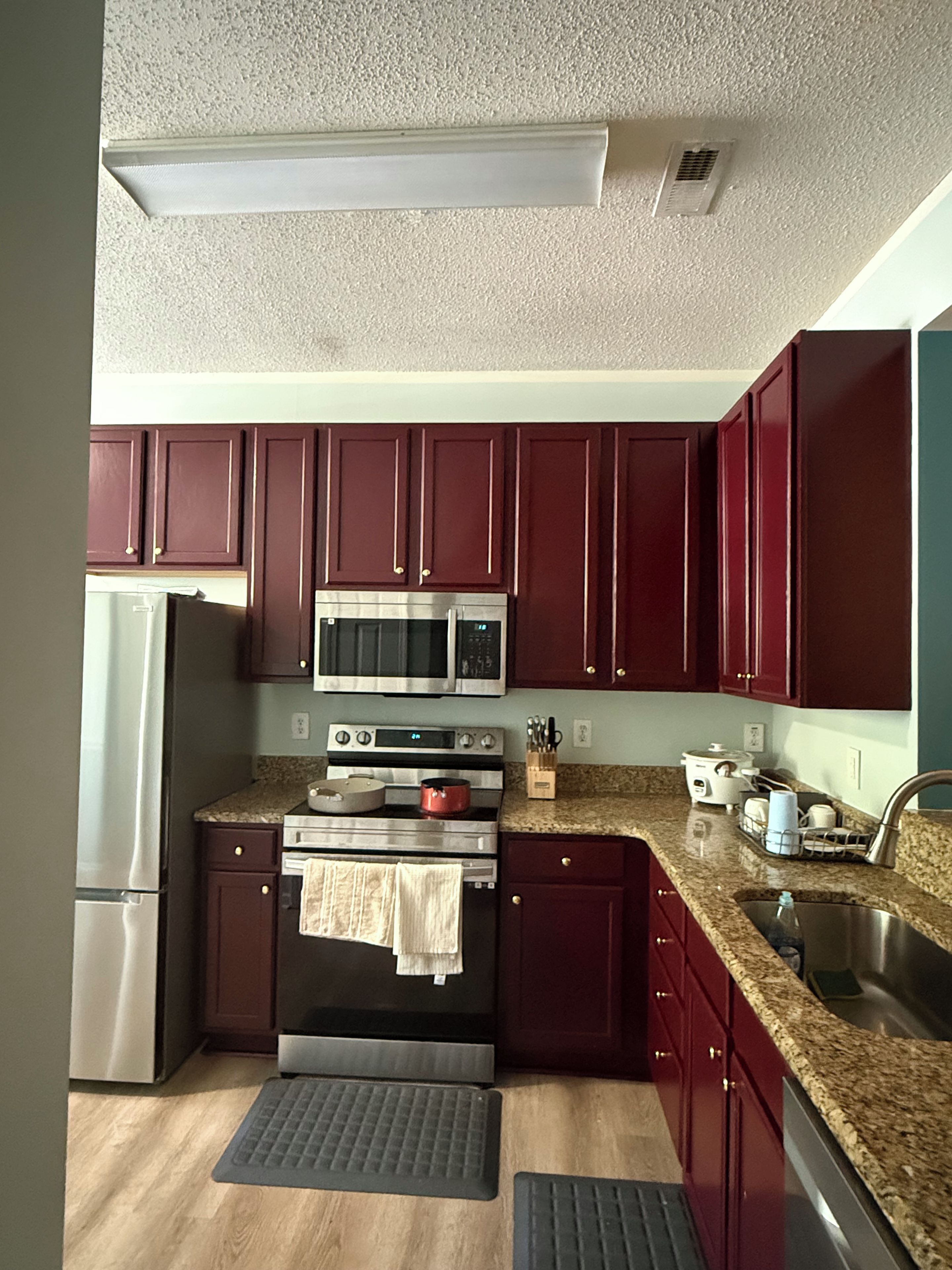 A kitchen with dark wooden cabinets, stainless steel appliances, a granite countertop, and a built-in oven.