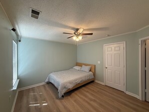 A bedroom with a bed, a ceiling fan, a door, and a window with blinds. - 3-bedroom townhome in perfect Cary Downtown with cool AC and comfort. (Cary)