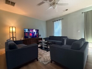 A living room with a flat-screen TV, two sofas, a coffee table, and a ceiling fan. - 3-bedroom townhome in perfect Cary Downtown with cool AC and comfort. (Cary)