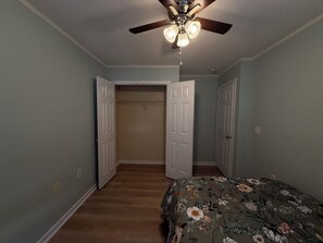 A bedroom with a bed, a ceiling fan, and two doors leading to other rooms. - 3-bedroom townhome in perfect Cary Downtown with cool AC and comfort. (Cary)