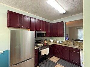 A modern kitchen with stainless steel appliances, dark wooden cabinets, and a granite countertop. - 3-bedroom townhome in perfect Cary Downtown with cool AC and comfort. (Cary)