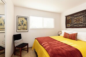 A bedroom with a bed, a chair, a window with blinds, and two pieces of wall art. - 3BR Desert Retreat: Pool, Deck, Games, Cabin & More w/ Private Hiking: 40 Acres (Joshua Tree)