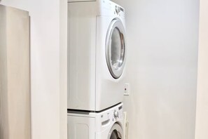 A front view of a white washing machine and dryer unit in a room. - 3BR Desert Retreat: Pool, Deck, Games, Cabin & More w/ Private Hiking: 40 Acres (Joshua Tree)