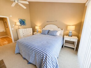 A bedroom with a bed, two bedside tables, a ceiling fan, a dresser, and a wall-mounted artwork. - Glen Arbor Waterfront | Lake Views + Fireplace (Glen Arbor)