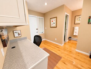 A kitchen with a granite countertop, wooden flooring, and a door leading to a bathroom. - Glen Arbor Waterfront | Lake Views + Fireplace (Glen Arbor)