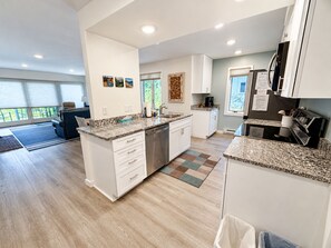 Une cuisine moderne avec des meubles blancs, des plans de travail en granit et un îlot central.