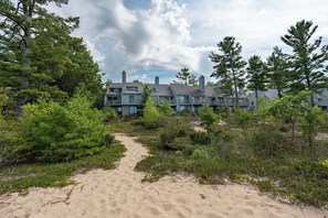 En ejendom ved stranden med en sti af sand, der fører til en række moderne bygninger.
