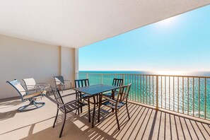 A balcony with a table and chairs, overlooking a body of water. - Ocean Reef 1703- Ocean O'peace (Panama City Beach)
