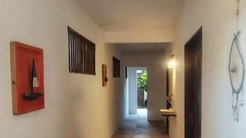 Un pasillo con suelo de baldosas, una puerta a la derecha y un aplique en la pared.