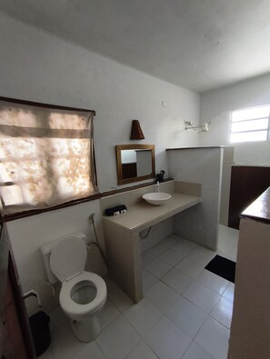 Ein Badezimmer mit Toilette, Waschbecken, Spiegel und Fenster.