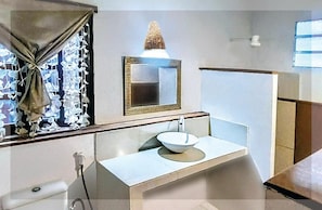 Ein Badezimmer mit einem weißen Waschbecken, einem Spiegel und einem Fenster mit Vorhängen.
