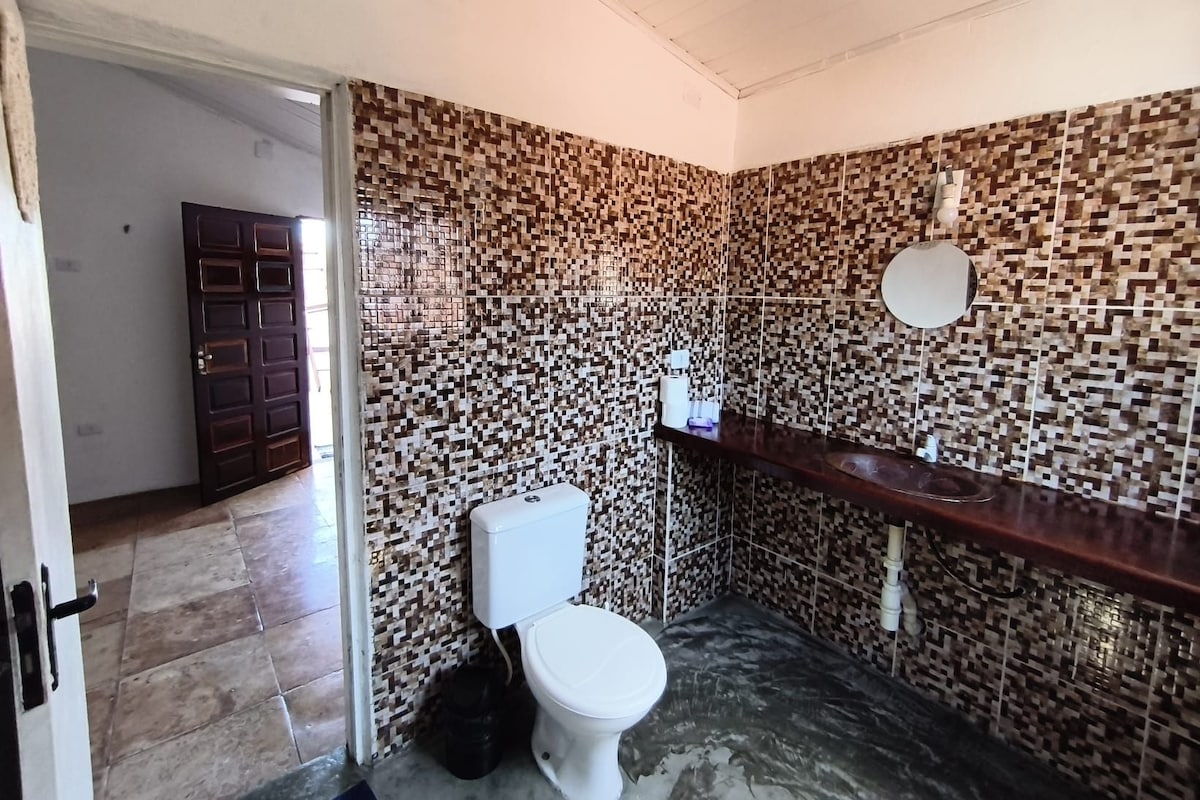 Ein Badezimmer mit gefliesten Wänden, Toilette, Waschbecken und Spiegel.