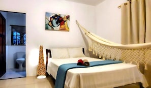 Ein Schlafzimmer mit einem Bett, einer Hängematte, einem Gemälde und einer Lampe.