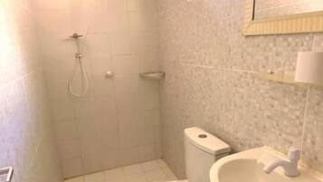 A small bathroom with a toilet, sink, and shower.