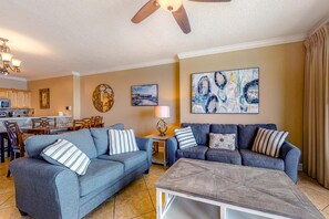 A living room with a sofa, a coffee table, and a dining area with a table and chairs. - Ocean Reef 1702- Gulf of Grace (Panama City Beach)