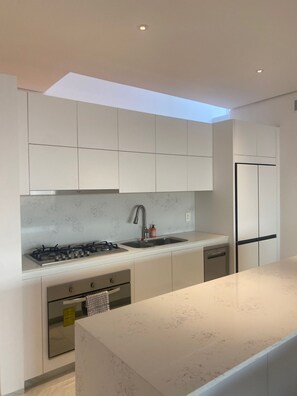 A modern kitchen with a gas stove, sink, and built-in appliances. - Luxury 3-Bedroom Condo | Private Rooftop | Ocean and Golf Views | Club Campestre by HCG (San José del Cabo)