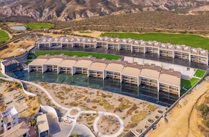 A modern hotel with a pool, surrounded by landscaped gardens and a golf course. - Luxury 3-Bedroom Condo | Private Rooftop | Ocean and Golf Views | Club Campestre by HCG (San José del Cabo)