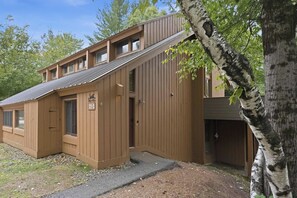 Een houten chalet met schuin dak, een klein terras en een garage.