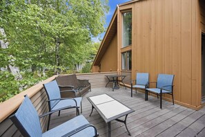 A wooden deck with outdoor furniture, including chairs and a table, and a large window. - 3BR Mountain Home Near Loon Mountain (Lincoln)