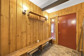 A wooden interior with a bench, a door, and a wall-mounted light fixture. - 3BR Mountain Home Near Loon Mountain (Lincoln)