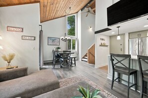 A spacious living area with a high ceiling, a dining table with chairs, and a kitchen with a refrigerator. - 3BR Mountain Home Near Loon Mountain (Lincoln)