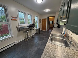 A kitchen with a granite countertop, stainless steel sink, and a bar stool.