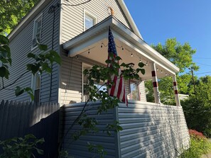 A two-story house with a porch, an American flag, and a picket fence.