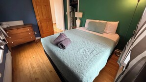 Ein Schlafzimmer mit Bett, Kommode, Tür und Deckenventilator.