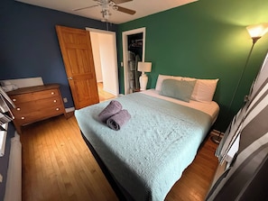 Ein Schlafzimmer mit Bett, Kommode, Tür und Deckenventilator.