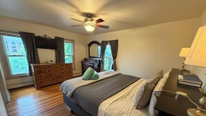 Ein Schlafzimmer mit Bett, Kommode, Schminktisch und Deckenventilator.