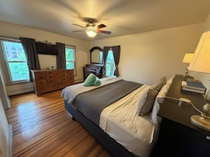 Ein Schlafzimmer mit Bett, Kommode, Schminktisch und Deckenventilator.