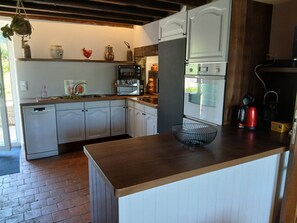 Een keuken met witte kastjes, een houten aanrecht, een hangplant, een waterkoker en een broodrooster.