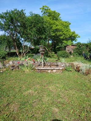 Een tuin met een vogelhuisje, een stenen muur en een houten constructie.