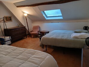 Ein Schlafzimmer mit einer Dachfensterkuppel, einem Bett, einem Sessel, einem Schminktisch und einem kleinen Tisch.