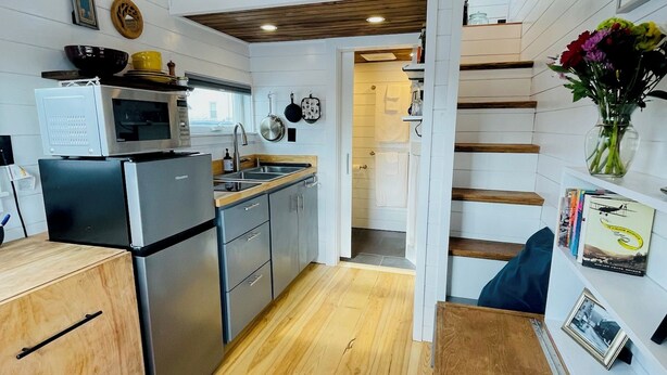 Una cocina compacta con armarios de madera, microondas integrado y refrigerador.