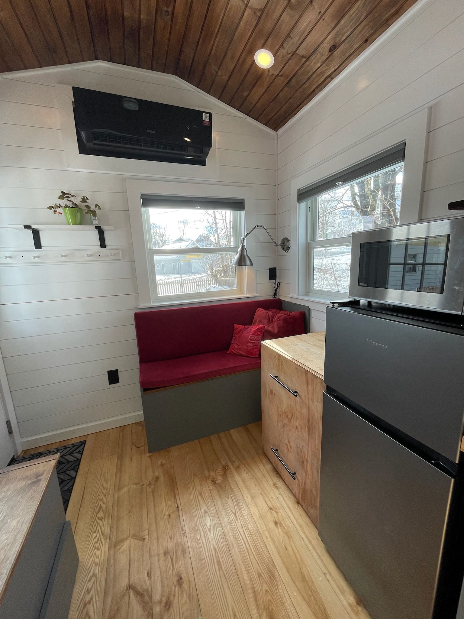 A compact kitchen with a built-in microwave, a red sofa, and wooden flooring.