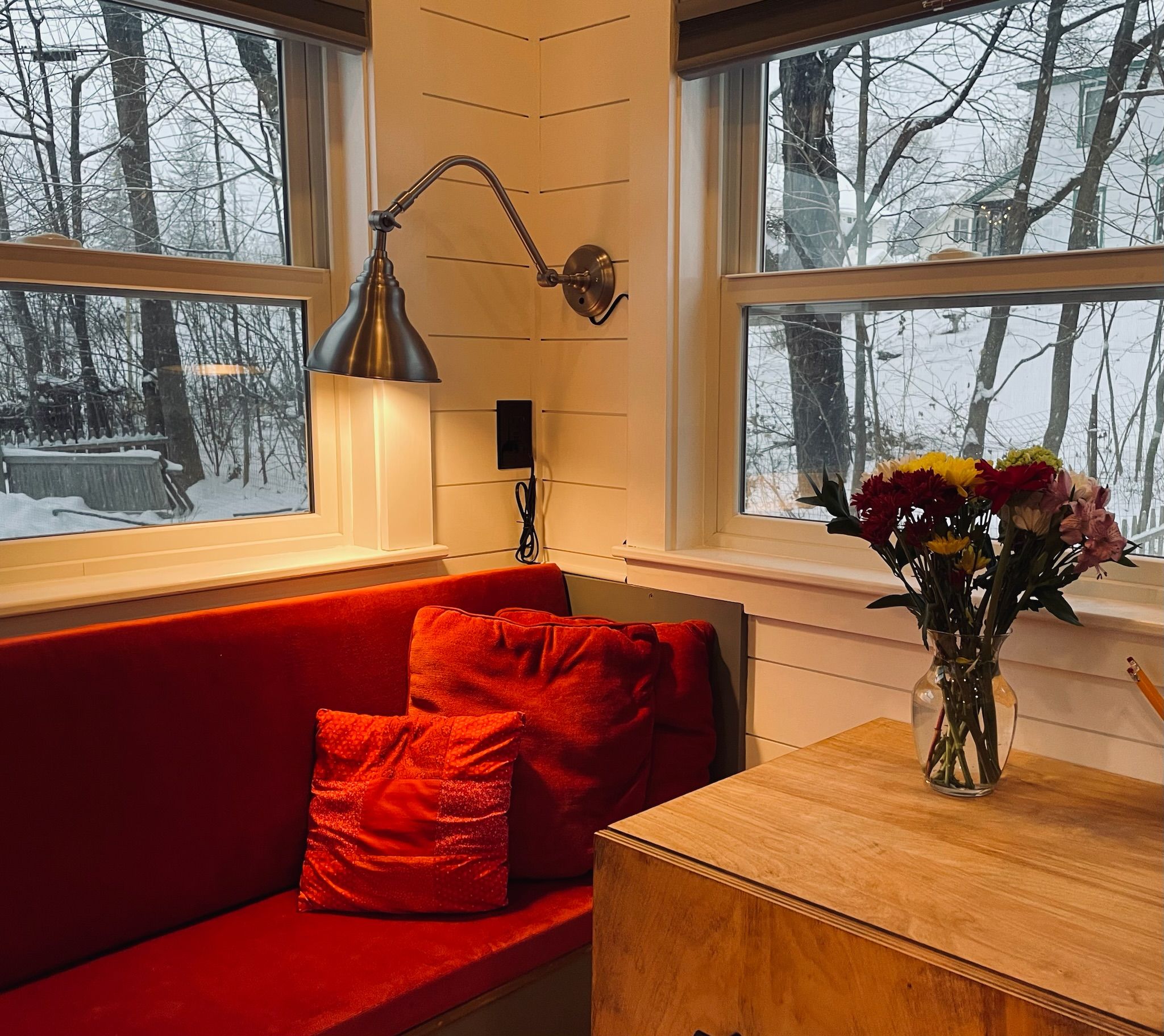 A room with a red sofa, a wooden table, and a vase of flowers.