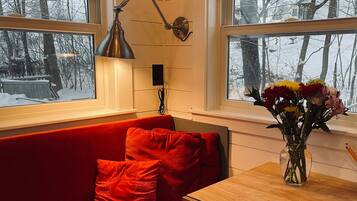 A room with a red sofa, a wooden table, and a vase of flowers.
