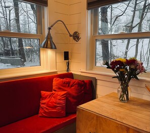 A room with a red sofa, a wooden table, and a vase of flowers.