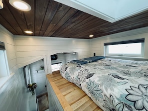 Un dormitorio pequeño con cama, ventana y una kitchenette.