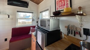 Una cocina compacta con microondas, un sofá rojo y un ventanal.