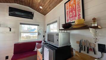 A compact kitchen with a microwave, a red couch, and a window.