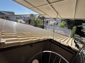 Eine Dachterrasse mit gewölbter Dachkonstruktion, einem Metallgeländer und Blick auf die umliegenden Gebäude.