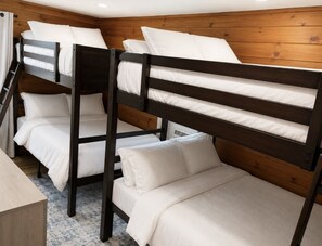 A bunk bed room with wooden walls and a carpeted floor. - Sea La Vie - Hot Tub, Huge Enclosed Private Deck, Sleeps 22, Close To Town (Ocean Beach)