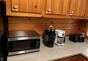 A kitchen with a microwave, coffee maker, and toaster on the countertop. - Sea La Vie - Hot Tub, Huge Enclosed Private Deck, Sleeps 22, Close To Town (Ocean Beach)