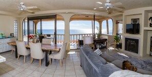 A spacious living area with a dining table, chairs, a sofa, and a fireplace. - Oceanfront Angel Villa with dipping pool, dog friendly and secure garage (B.C.)
